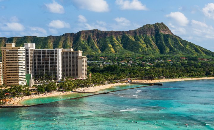 A beach and hotel in Honolulu with volcano background